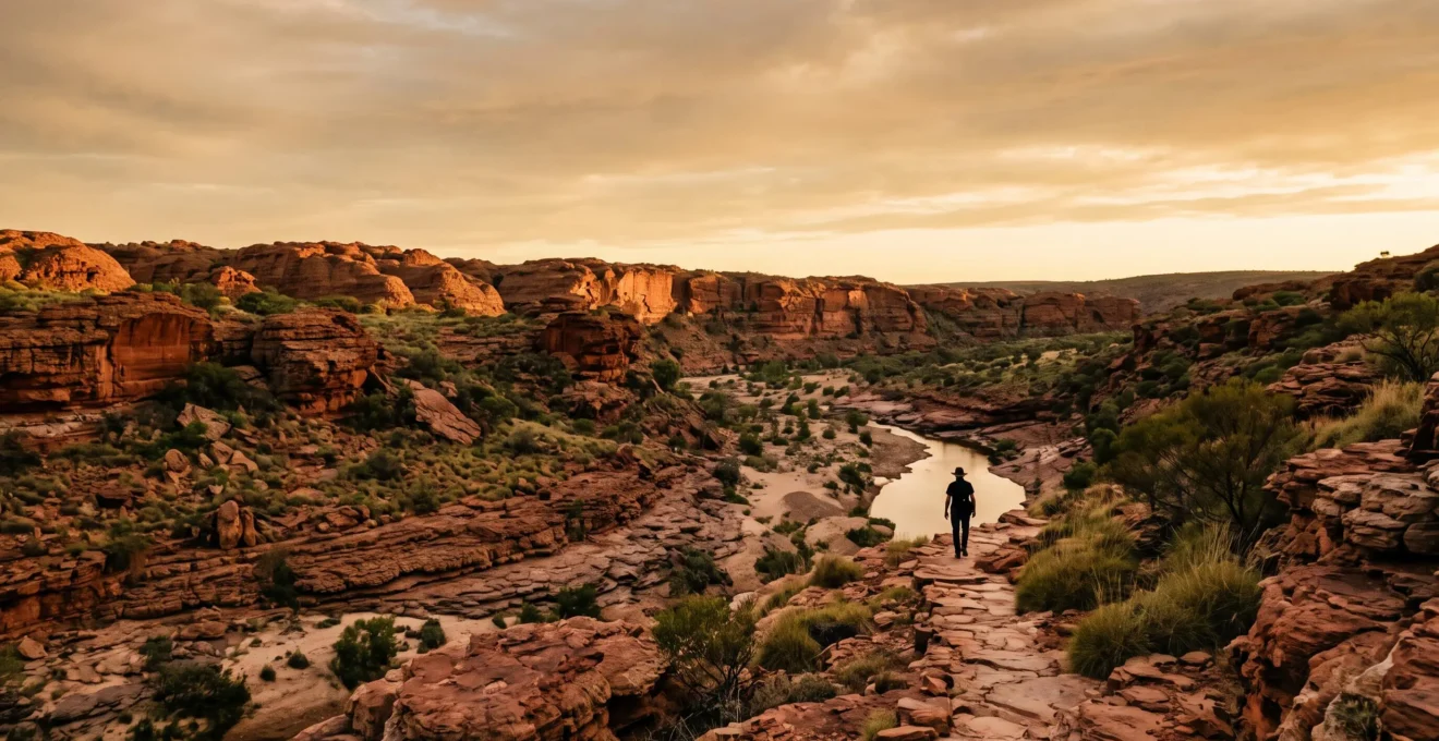 A lone traveler walking through an ancient ochre-red rock landscape at golden hour, symbolizing deep time and continuous Indigenous culture