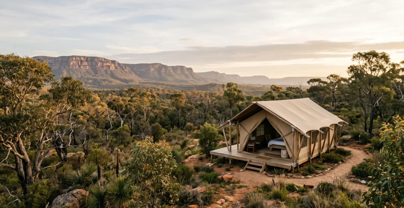A single canvas safari tent nestled in an ancient, remote Australian wilderness landscape at dawn, with no other structures in sight