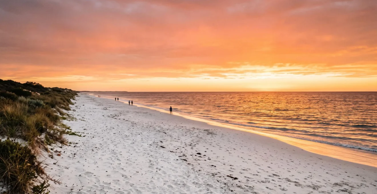 Wide golden-hour view of a nearly empty Perth beach with turquoise Indian Ocean water and dramatic sunset sky